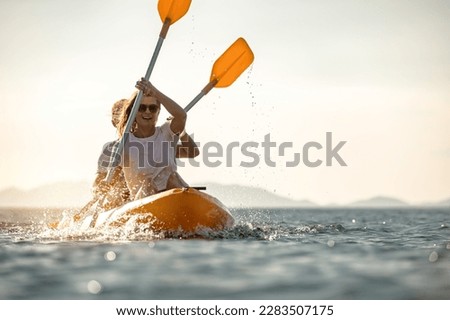 Young couple walks on sea kayak or canoe at calm sunset sea