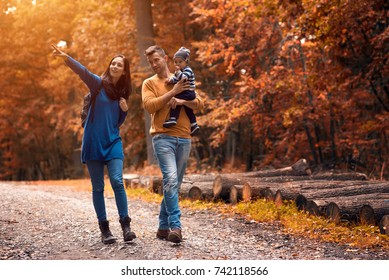 A Young Couple Walks In The Woods With A Little Boy