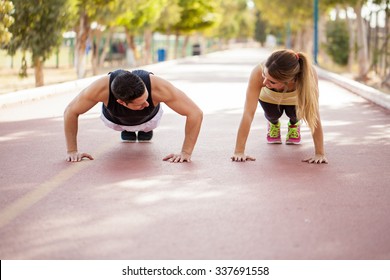 Стоковая фотография: Young couple warming up and doing some push ups together outdoors