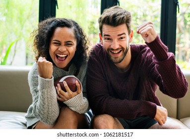 Young Couple Watching American Football At Home