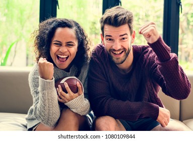 Young Couple Watching American Football At Home