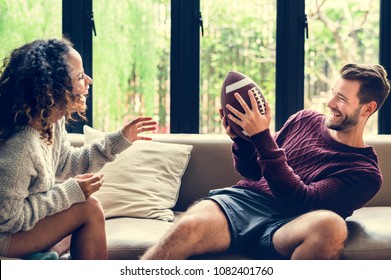 Young Couple Watching American Football At Home