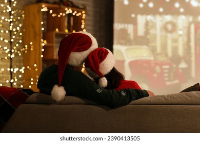 Young couple watching Christmas movie on projector screen at home, back view - Powered by Shutterstock