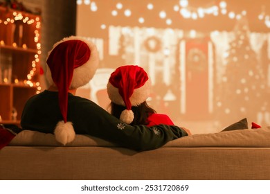 Young couple watching Christmas movie on projector screen at home, back view - Powered by Shutterstock