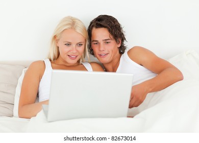 Young Couple Watching A Movie With A Laptop In Their Bedroom