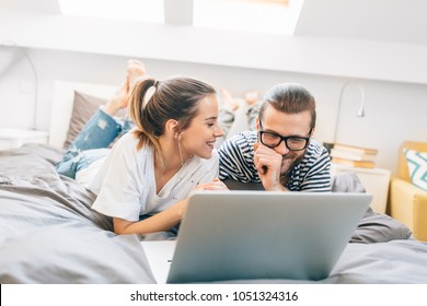 Young Couple Watching A Movie On Their Laptop In Bed 
