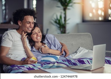 Young couple watching a movie on their laptop in bed