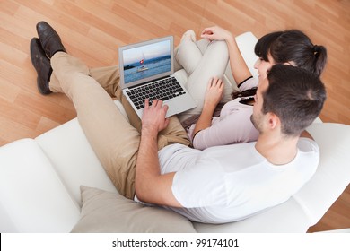 Young Couple Watching Photos On Laptop In Couch At Home