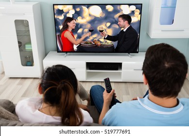 Young Couple Watching Romantic Movie On Television Together At Home