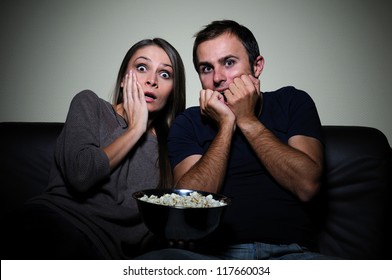 Young Couple Watching Scary Movie On Tv