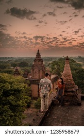 Young Couple Watching Sunrise From Rooftop Pagoda, Bagan Old Ruins Temple's And Pagoda During Sunrise, Man And Woman Couple Watching Sunrise In Old Bagan