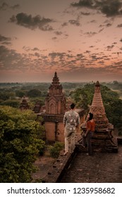 Young Couple Watching Sunrise From Rooftop Pagoda, Bagan Old Ruins Temple's And Pagoda During Sunrise, Man And Woman Couple Watching Sunrise In Old Bagan