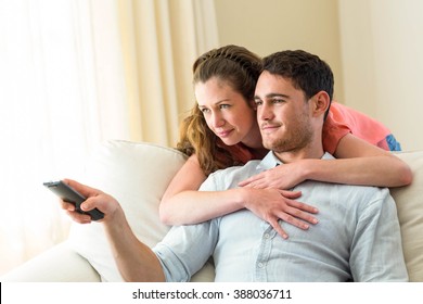 Young couple watching television together on sofa in living room