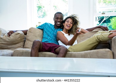 Young Couple Watching Television While Relaxing On The Sofa