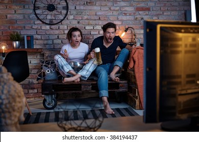 Young couple watching tv at home, jittering.