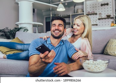 Young Couple Watching TV On A Sofa At Home