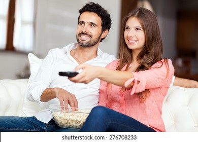 Young Couple Watching Tv On A Sofa 