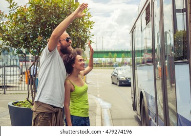 Young Couple Waving Goodbye To Their Friends On The Bus At Bus Station