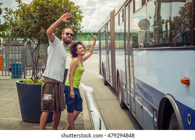 Young Couple Waving Goodbye To Their Friends On The Bus At Bus Station