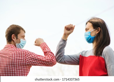 Young Couple Wear Face Masks Outdoors. Social Distancing. Friends Greeting With Elbows Outdoors. New Real Life. Coronavirus Quarantine. Fight Coronavirus. Coronavirus Epidemic. Friends In Safety Mask.