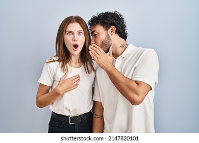 Young couple wearing casual clothes standing together hand on mouth telling secret rumor, whispering malicious talk conversation  - Shutterstock ID 2147820101