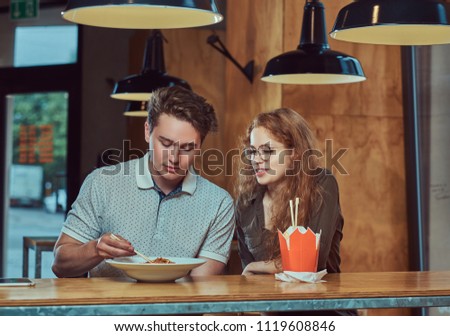 Young couple wearing casual clothes eating spicy noodles in an Asian restaurant. 