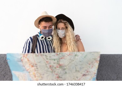 Young Couple Wearing Face Mask And Holding Travel Map - Travelers People Enjoying First Trip After Corona Virus Outbreak - Restart Tourism And Love Relationship Vacation Lifestyle Concept