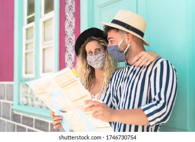 Young Couple Wearing Face Mask And Holding Travel Map - Travelers People Enjoying First Trip After Corona Virus Outbreak - Restart Tourism And Love Relationship Vacation Lifestyle Concept