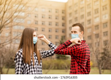 Young Couple Wearing Face Mask Outdoors Say Hello With Elbows Outdoors. No Hugs, No Kisses, No Shake Hands. Friends Shaking Elbows Outdoors. Greeting With Elbows.