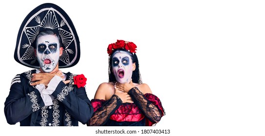 Young couple wearing mexican day of the dead costume over background shouting suffocate because painful strangle. health problem. asphyxiate and suicide concept. 