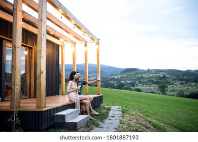 Young couple with wine outdoors, weekend away in container house in countryside.