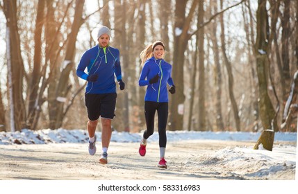 Young Couple In The Winter Running Together In Nature