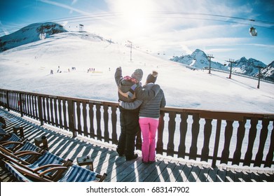 Young Couple In Winter Vacation At Snow Resort Mountain - Skiers Tourists Relaxing In Ski Slope Chalet - Travel Concept - Soft Focus On Him - Contrast Retro Filter With Fisheye Lens Distortion