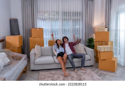 Young Couple Woman And Man Sitting On Sofa Together Happy Look On Ceiling During Move To New House