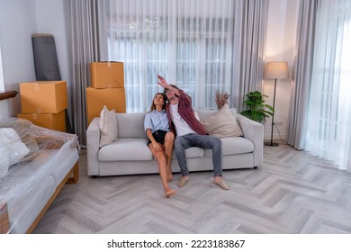 Young Couple Woman And Man Sitting On Sofa Together Happy Look On Ceiling During Move To New House