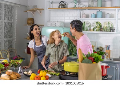 Young Couple Working With Grand Mom To Prepare Meal At Home. Happy Family Is Cooking Breakfast With Healthy Food Together