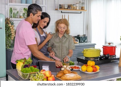 Young Couple Working With Grand Mom To Take Online Cooking Course And Prepare Meal At Home. Happy Family Is Cooking Breakfast With Healthy Food Together