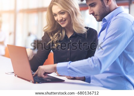 Young couple working together on a laptop in the office. Teamwork concepts.