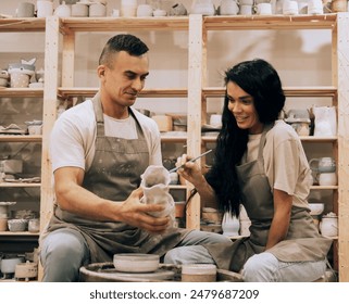 A young couple works in a pottery workshop. Painting a vase. - Powered by Shutterstock