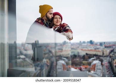 Young couple wrapped in blanket standing and hugging outdoors on balcony, shot through glass. - Powered by Shutterstock