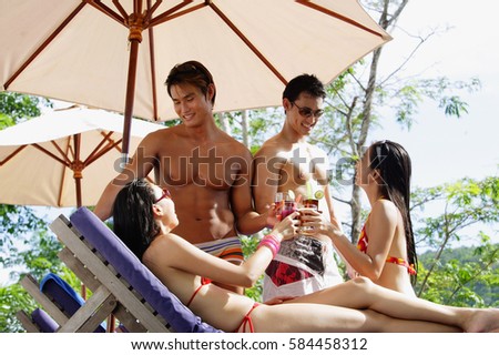 Young couples in swimwear, toasting with drinks