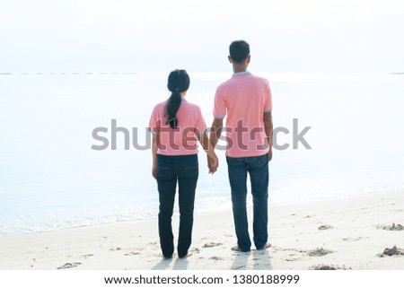 Young couples walk hand in hand on the beach. In the summer holidays