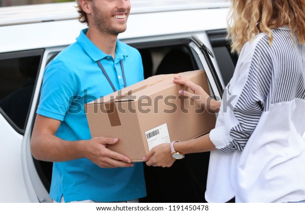 Young courier\
delivering parcel to woman\
outdoors
