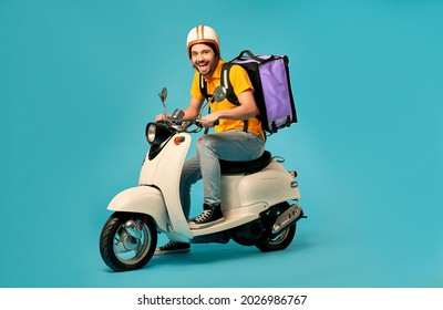 Young courier, delivery man in uniform with thermo backpack on a moped isolated on blue background. Fast transport express home delivery. Online order.