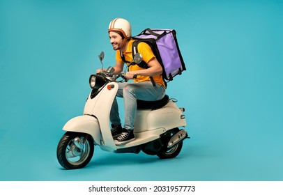 Young courier, delivery man in uniform with thermo backpack on a moped isolated on blue background. Fast transport express home delivery. Online order. - Shutterstock ID 2031957773