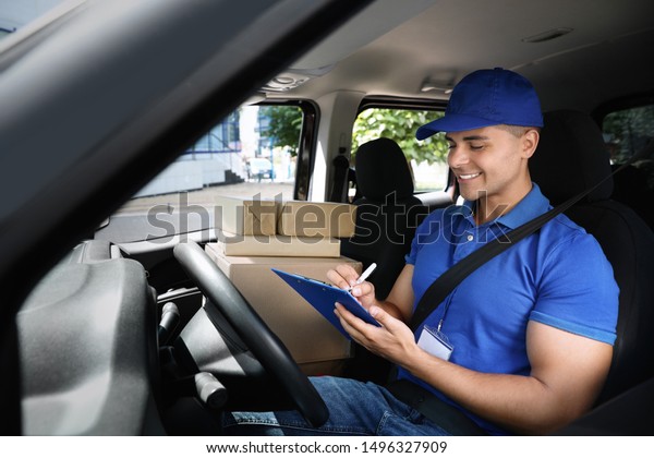 Young
courier with parcels and clipboard in delivery
car