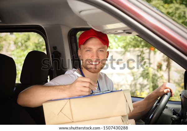 Young\
courier with parcels and clipboard in delivery\
car