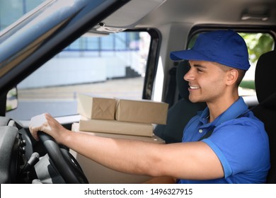 Young Courier With Parcels In Delivery Car