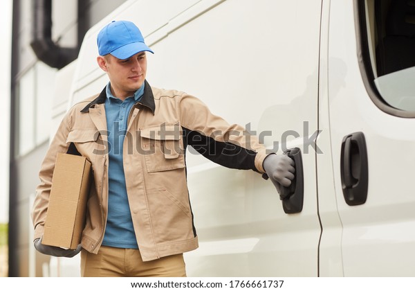 Young\
courier in uniform delivering parcels by the\
van