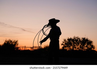 Young cowboy with rope in Texas sunset on ranch for childhood western lifestyle. - Powered by Shutterstock